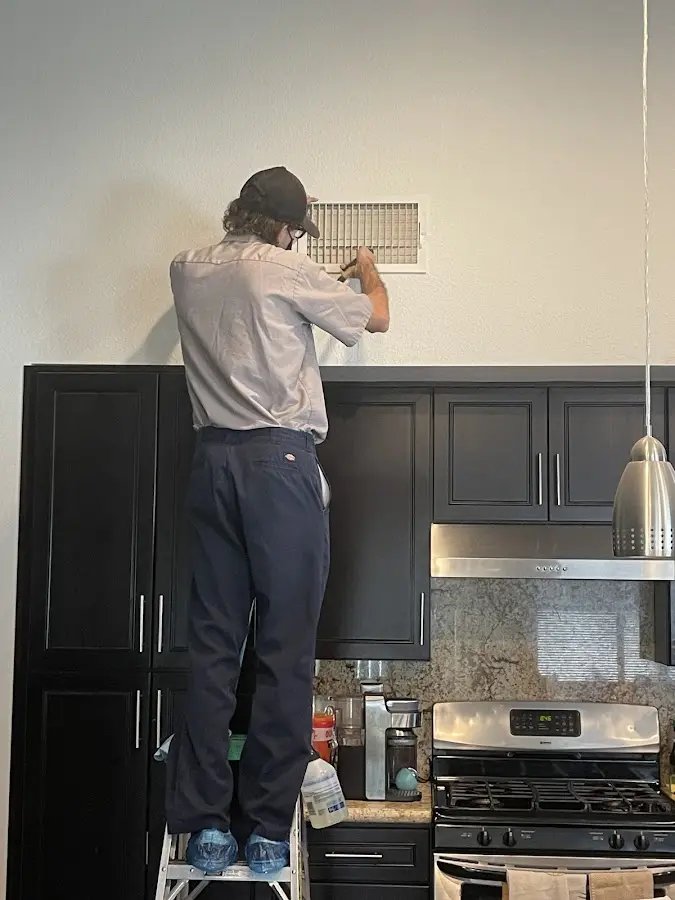 Technician inspecting an air vent during HVAC service in Hockinson